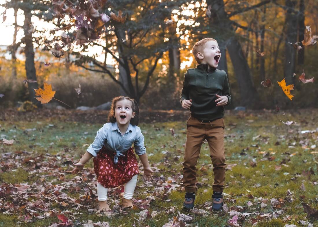 Family having fun jumping in autumn leaves.